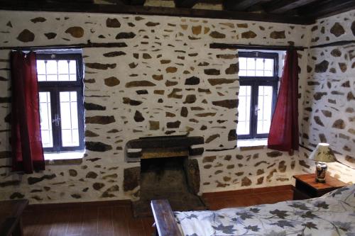 a bedroom with a stone wall with two windows at Al Monte Hotel in Vronterón