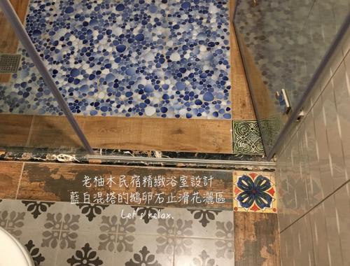 a bathroom with a shower with blue and white tiles at Home & Teak Homestay in Jinning