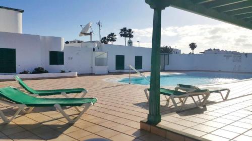 a patio with two chairs and a swimming pool at Bungalow King in Puerto del Carmen