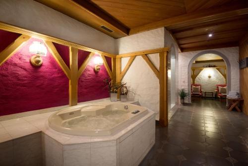 ein großes Bad mit einer großen Badewanne in einem Zimmer in der Unterkunft Der Jagdhof in St. Johann im Pongau
