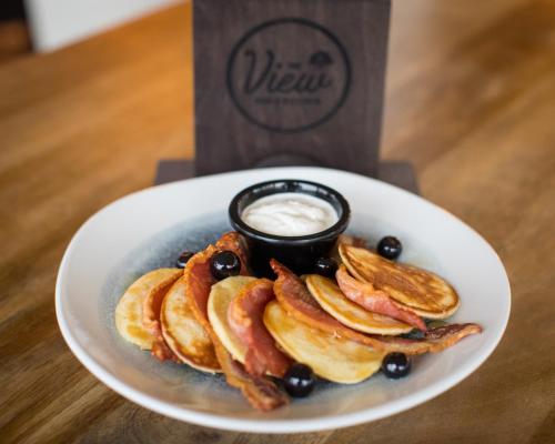 a plate of pancakes with bacon and a drink at The View in Welwyn Garden City