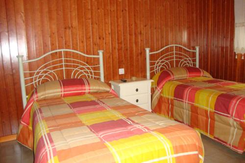 コルテガナにあるB&B Cervantesのウッドパネルの壁の客室で、ベッド2台が備わります。