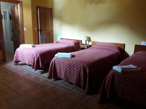 3 camas en una habitación con sábanas rosas en La Casa Vieja en Valdeón, en Soto de Valdeón