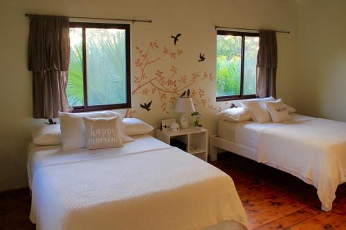two beds in a room with two windows at Cabañas La Casa de Pucha in Pedasí Town
