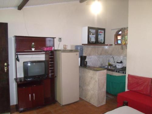 a kitchen with a refrigerator and a tv in a room at Suítes Brisa Mar in Cabo Frio