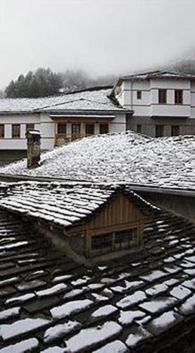 a snow covered roof of a house with snow on it at Katogi Averoff Hotel & Winery in Metsovo