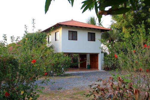 a white house with a red roof at Cabañas La Casa de Pucha in Pedasí Town
