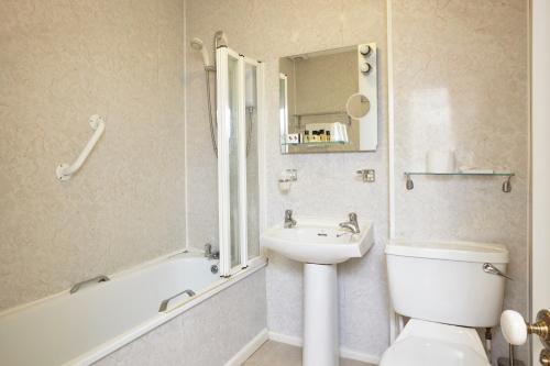 a bathroom with a sink and a toilet and a bath tub at The Grange B&B in Shanklin