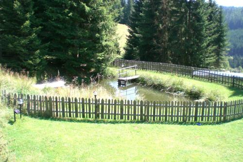 a wooden fence in a yard with a pond at Rüggenhütte in Hochfeistritz