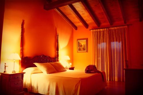 a bedroom with a bed with an orange wall at Alcor del Roble in Collado