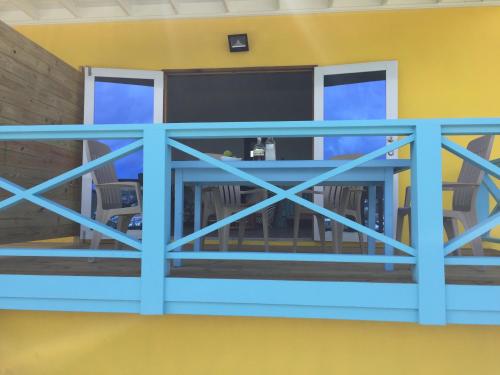 a balcony with a blue railing and chairs at CasaCalypso Grenada in Belmont