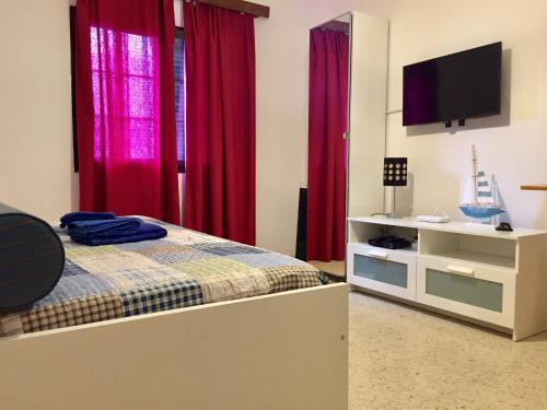 アリエタにあるPura Studioの赤いカーテン、ベッド、テレビが備わるベッドルーム1室が備わります。