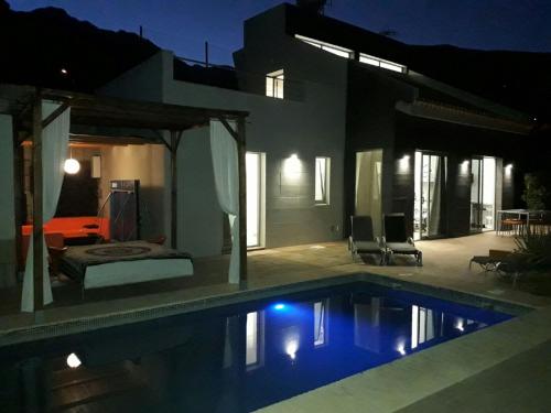 a swimming pool in front of a house at night at VILLA Atlantico Views in Candelaria