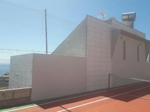 a white building with a fence on a tennis court at VILLA Atlantico Views in Candelaria