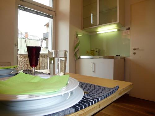 a table with a glass of wine and plates on it at Lovely, central apartment with balcony in Innsbruck