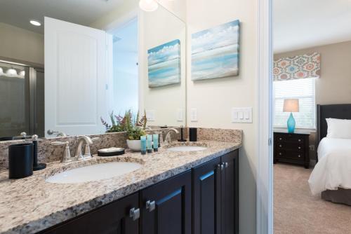 La salle de bains est pourvue de 2 lavabos et d'un grand miroir. dans l'établissement Vibrant Home by Rentyl Near Disney with Private Pool, Themed Room & Resort Amenities - 401N, à Orlando