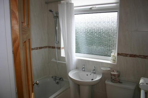 a bathroom with a sink and a toilet and a window at Beach Links in Prestatyn