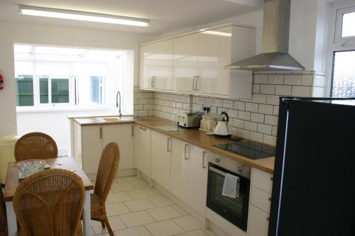 a kitchen with white cabinets and a table with chairs at Beach Links in Prestatyn