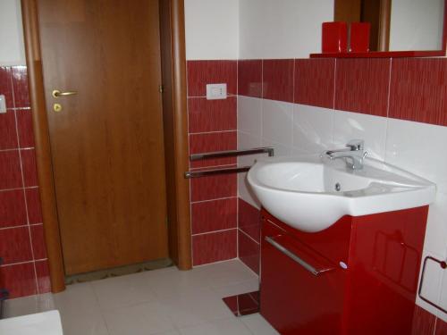 łazienka z białą umywalką i czerwonymi kafelkami w obiekcie Matteo's home w mieście Donnalucata
