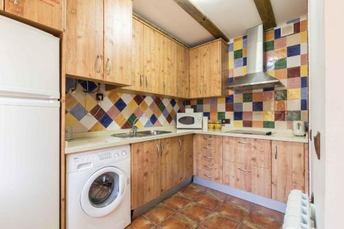 a kitchen with wooden cabinets and a washer and dryer at Finca La Celada in Moratalla
