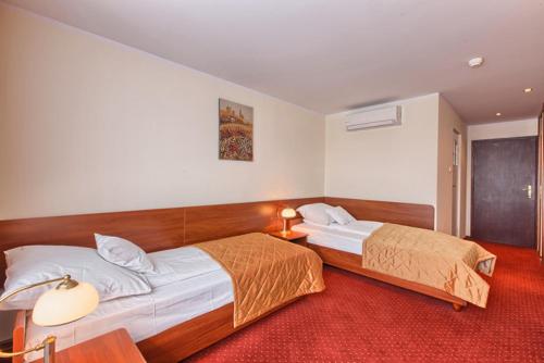 a bedroom with two beds and a red carpet at Hotel Jubilat in Zamość