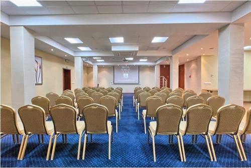a room with a bunch of chairs and a screen at Hotel Jubilat in Zamość