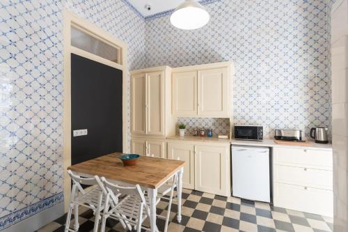 a kitchen with white cabinets and a table with stools at Príncipe Real Guest House in Lisbon