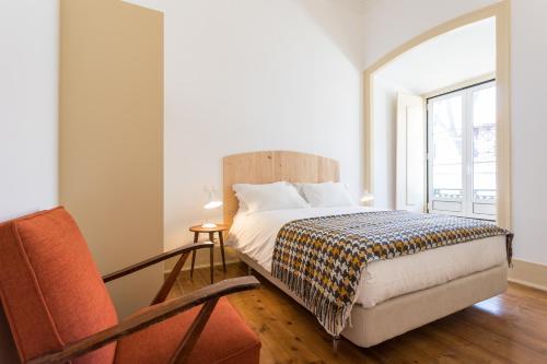 a bedroom with a bed and a chair and a window at Príncipe Real Guest House in Lisbon
