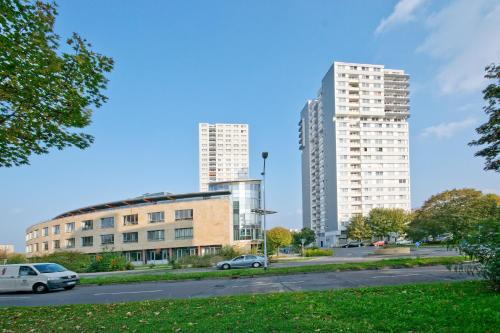 two tall buildings in a city with cars on the street at GWG City Apartments III in Halle-Neustadt