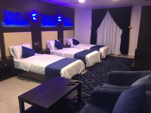 a hotel room with three beds and a couch at Holiday Furnished Units in Dammam