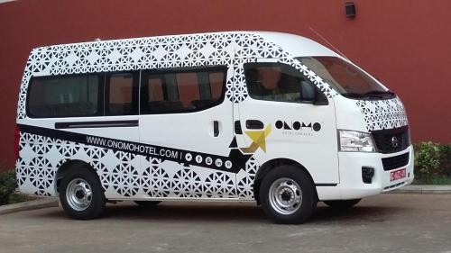 a white van parked in front of a red building at ONOMO Hotel Conakry in Conakry
