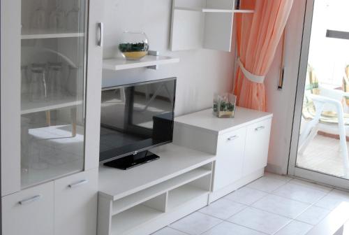 ネルハにあるCorona 204 Apartments Casasolの白いキャビネットとオレンジのカーテンが備わるキッチン
