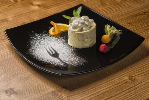 a black plate with a dessert on a table at Martinshof berg herz hotel in San Giovanni in Val Aurina