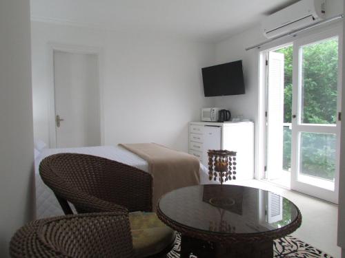 a living room with a table and a bed and a window at San Clemente Residence in Gramado