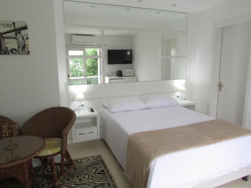 a white bedroom with a bed and a table and chairs at San Clemente Residence in Gramado