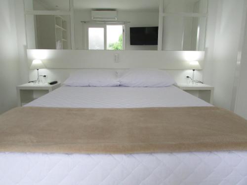 a bedroom with a large white bed with two night stands at San Clemente Residence in Gramado