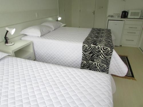 a bedroom with two beds and a night stand at San Clemente Residence in Gramado