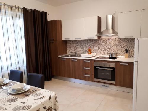 a kitchen with wooden cabinets and a table with a tablecloth on it at D Bay Apartments in St. Paul's Bay