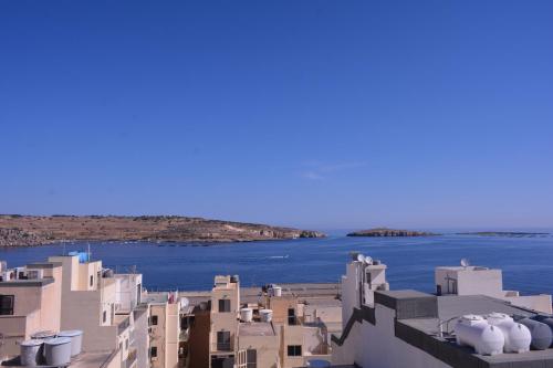 a group of white buildings with water in the background at D Bay Apartments in St. Paul's Bay