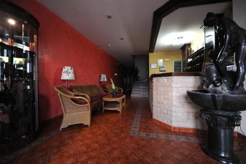 a lobby with red walls and a couch and a sink at Hotel Montearoma in Valverde del Camino
