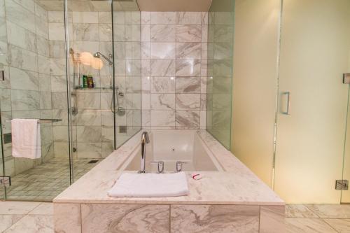 ein Bad mit einer Badewanne und einer Dusche mit einem Waschbecken in der Unterkunft Dream Penthouse at Palms Place in Las Vegas