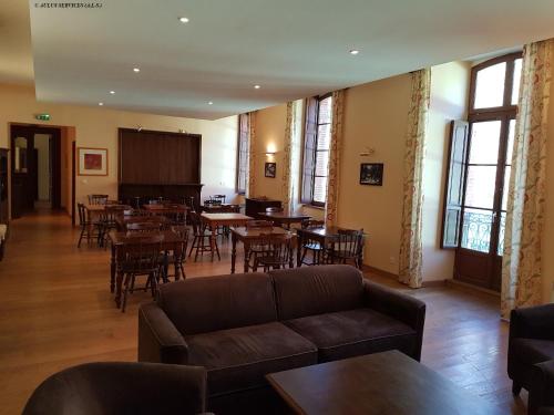 a living room with a couch and tables and chairs at Résidence Grand Hôtel in Aulus-les-Bains