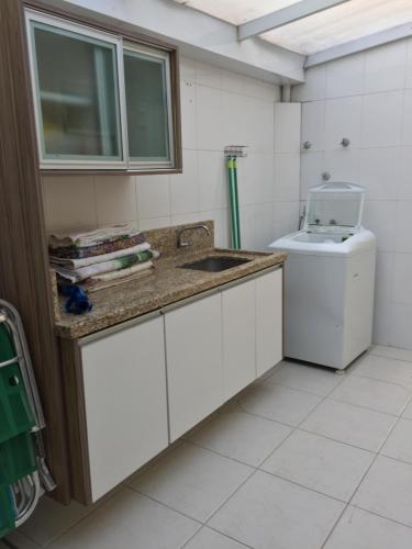 a kitchen with a sink and a washing machine at Casa do Samir in Palhoça