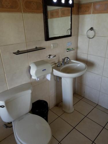 a bathroom with a toilet and a sink at Hotel Monte Campana Heredia in Birrí