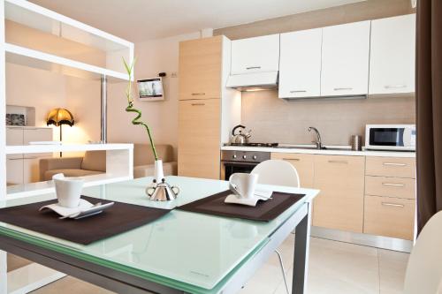 a kitchen with a glass table and white cabinets at Abitare in Vacanza in La Caletta