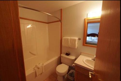 a bathroom with a white toilet and a sink at Executive House Suites Hotel & Conference Centre in High Level