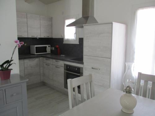 une cuisine avec des placards blancs et une table blanche avec des chaises dans l'établissement STUDIO 2 PERS PROCHE PLAGE ET COMMERCES, à Sainte-Marie de Ré