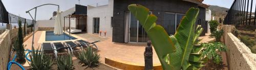 a palm tree in front of a house with a pool at VILLA Atlantico Views in Candelaria