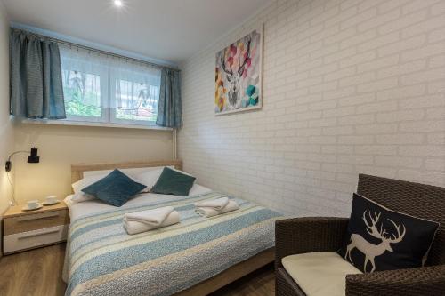 a bedroom with a bed and a chair and a window at Apartamentylove - Apartament Zborowski Centrum, 100m do Krupówek in Zakopane