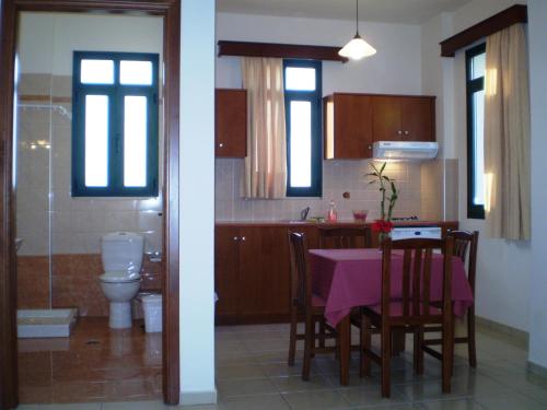 uma cozinha com uma mesa com uma toalha de mesa cor-de-rosa em Roubini Apartments em Falasarna